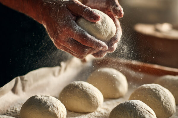baker-shaping-donut-dough-into-round-balls-on-a-pa