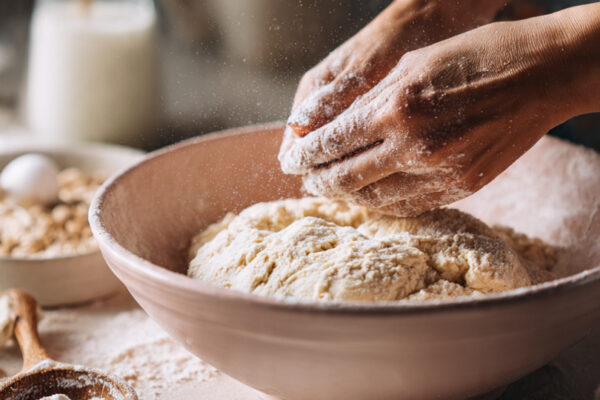 hands-kneading-soft-donut-dough-in-a-pastel-mixing